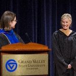 A faculty member smiles as she receives acknowledgment from event speaker